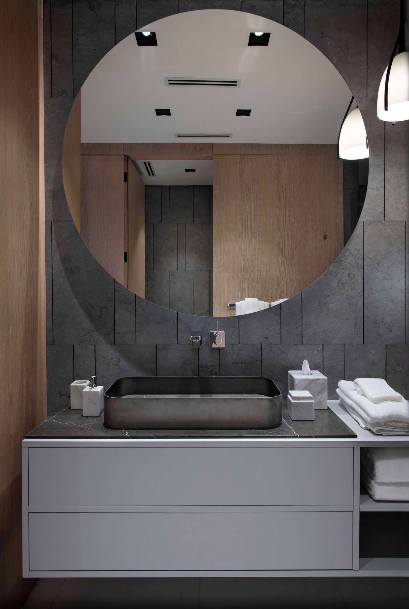 Custom dark wood walk-in closet with integrated LED shelf lighting and grey matte drawers.